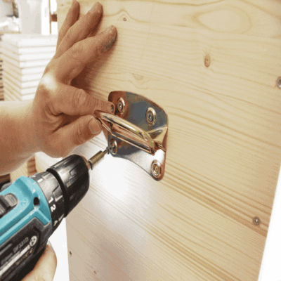 Hand montiert Klappgriff an Bienenstock mit Akku-Schrauber.