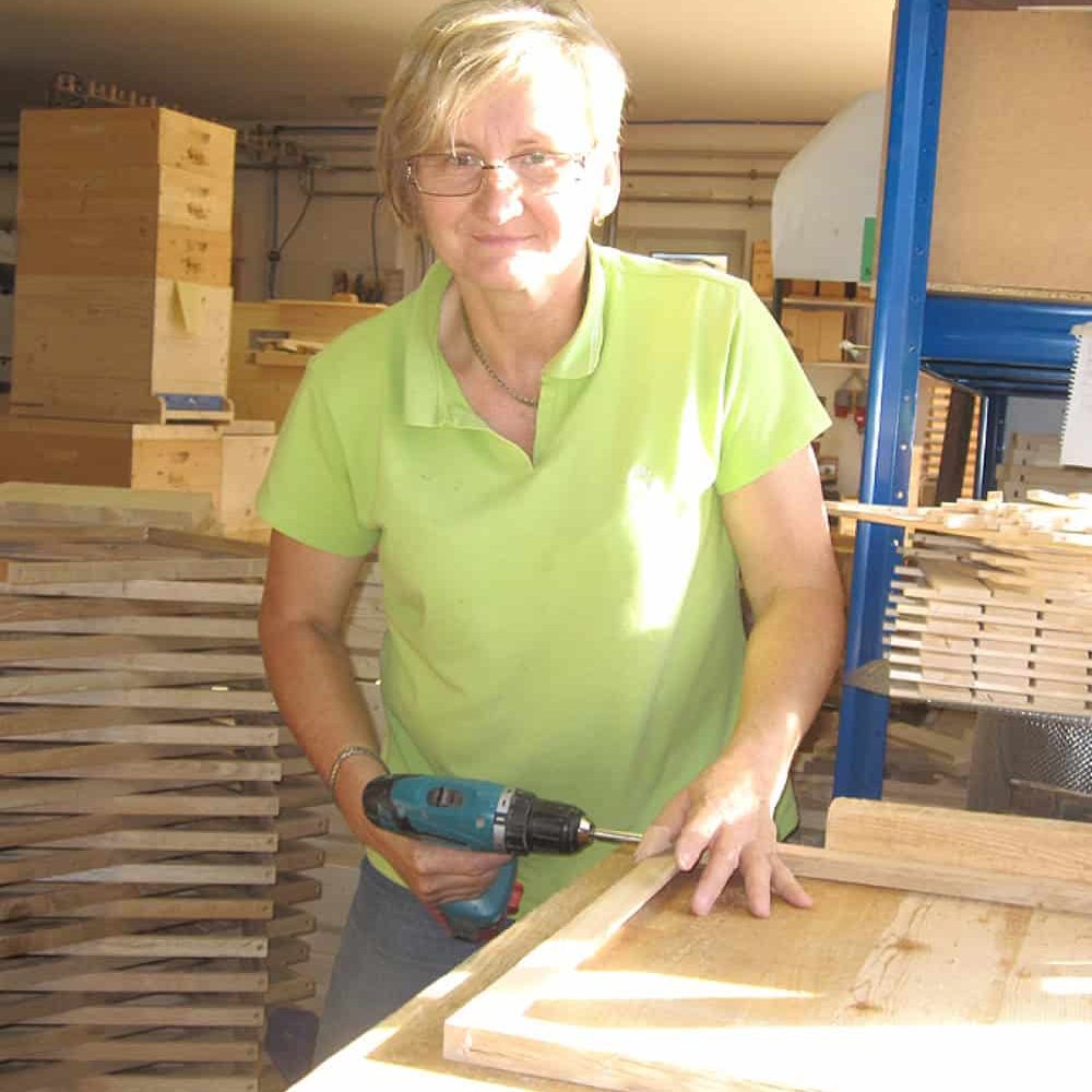 Frau arbeitet mit Bohrmaschine an Holz in der Werkstatt.